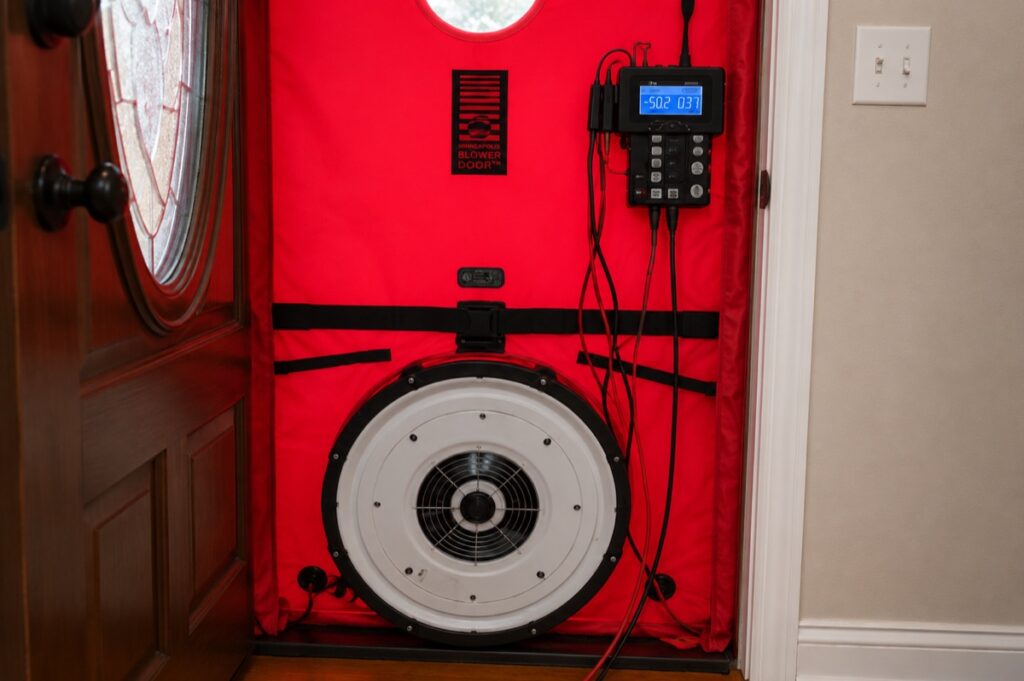 Blower door manometer displaying a home's CFM50 air leakage reading