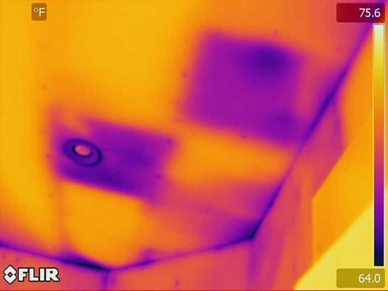Recessed ceiling light and ceiling inspected for hidden air leaks during a home energy audit